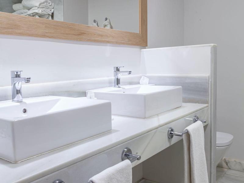 Bagno moderno con due lavabi quadrati e grande specchio con cornice in legno.