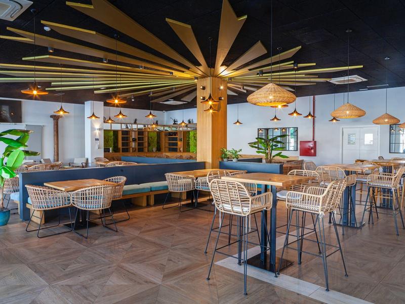 Ristorante moderno con grandi tavoli, sedie in metallo e illuminazione decorativa originale.