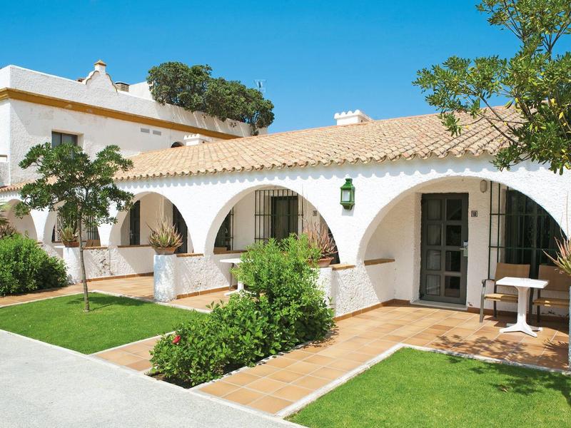 Casa accogliente con archi bianchi, giardino verde e terrazza soleggiata.