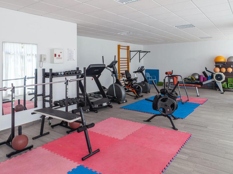 Palestra ben attrezzata con tappetini colorati e vari attrezzi per allenamento.