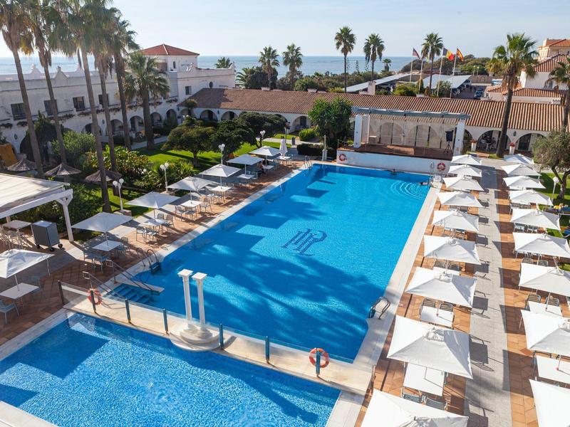 Piscina all'aperto con sdraio e ombrelloni in un hotel soleggiato.