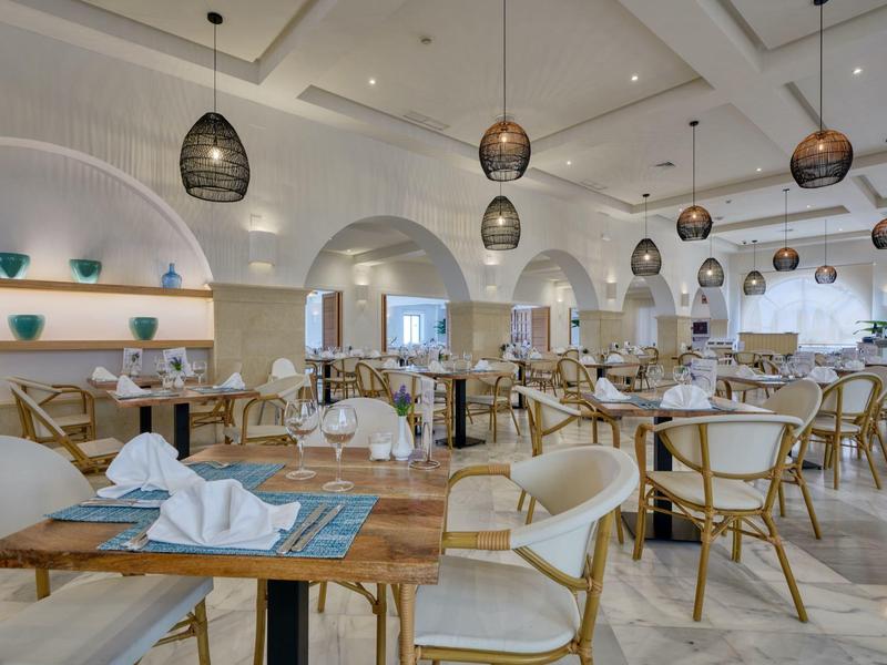 Ristorante moderno con tavoli in legno e sedie bianche in un ambiente luminoso e spazioso.