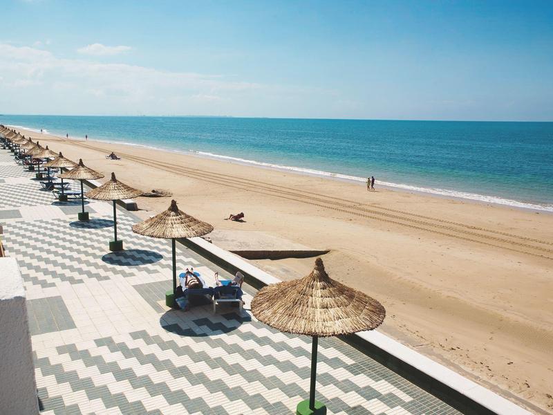 Spiaggia calma con ombrelloni e lettini vista mare, vista da una terrazza.