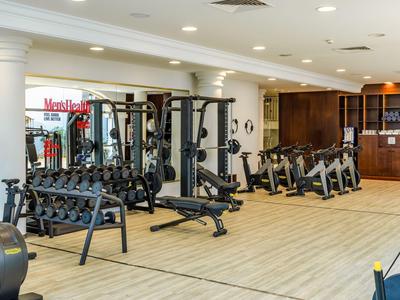 Moderner Fitnessraum im Hotel mit verschiedenen Trainingsgeräten und Holzfußboden.