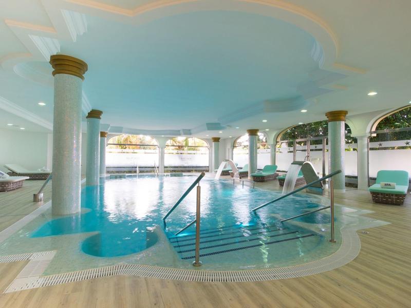 Overdekt zwembad met zuilen, whirlpool en houten vloer in een hotel