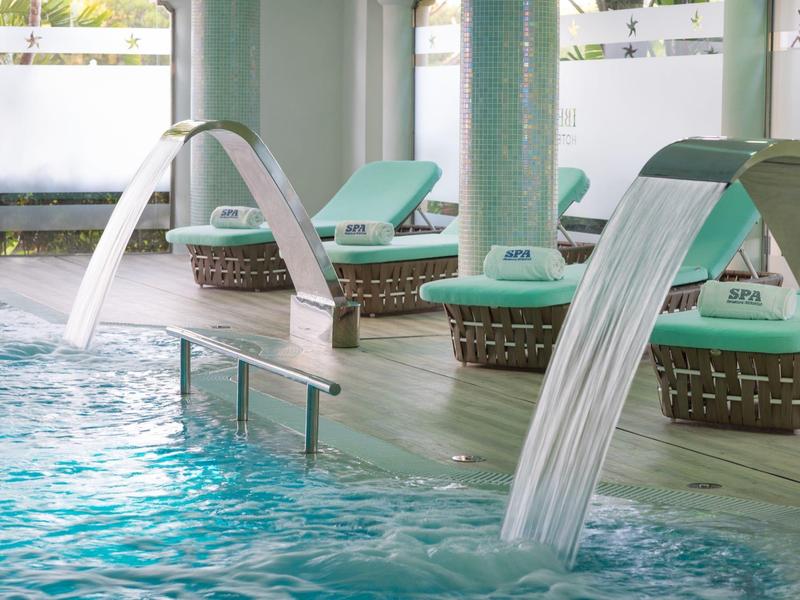 Overdekt zwembad met waterfonteinen en ligstoelen op houten terras