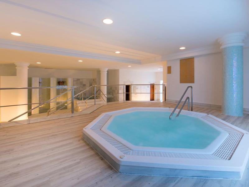 Binnenruimte met moderne jacuzzi in een lichte kamer met houten vloer en verlichting