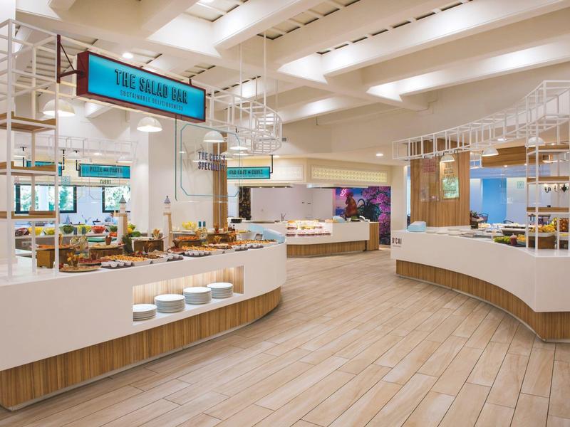 Lichte, moderne buffetruimte met houten vloer en witte toonbanken in een hotel.