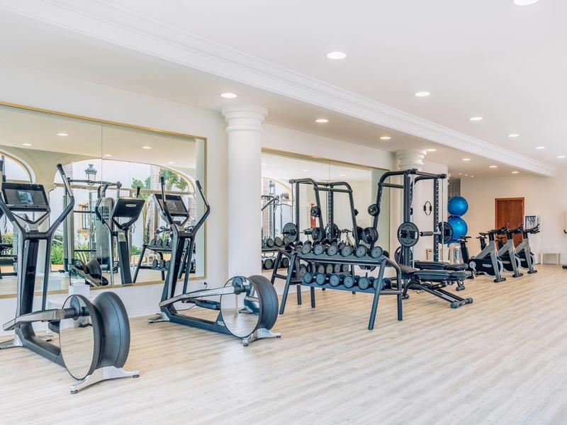 Lichte fitnessruimte met moderne apparatuur en halters in een hotel.