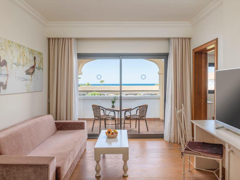 Gezellige kamer met bank, tafel en balkon met uitzicht op zee in een hotel.