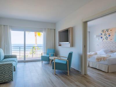 Helles Wohn- und Schlafzimmer mit Meerblick, Holzfußboden, blauen Sitzmöbeln und modernem Design.