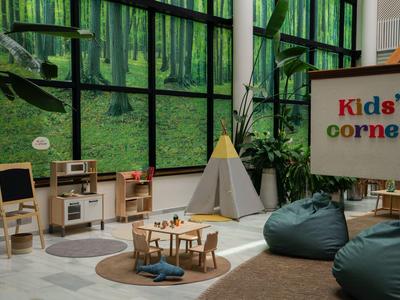 Kinderhoek met speelruimte, tafels, stoelen en comfortabele zitzakken in een lichte kamer.