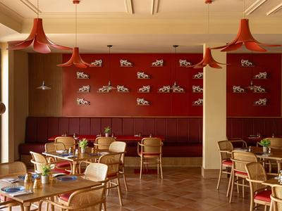 Modernes Hotelrestaurant mit roten Lampen, Holztischen und Zebradekor an der Wand.