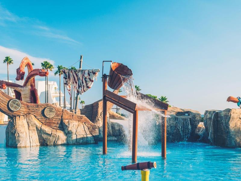 Waterpark met glijbanen en rotsstructuren onder een zonnige hemel.