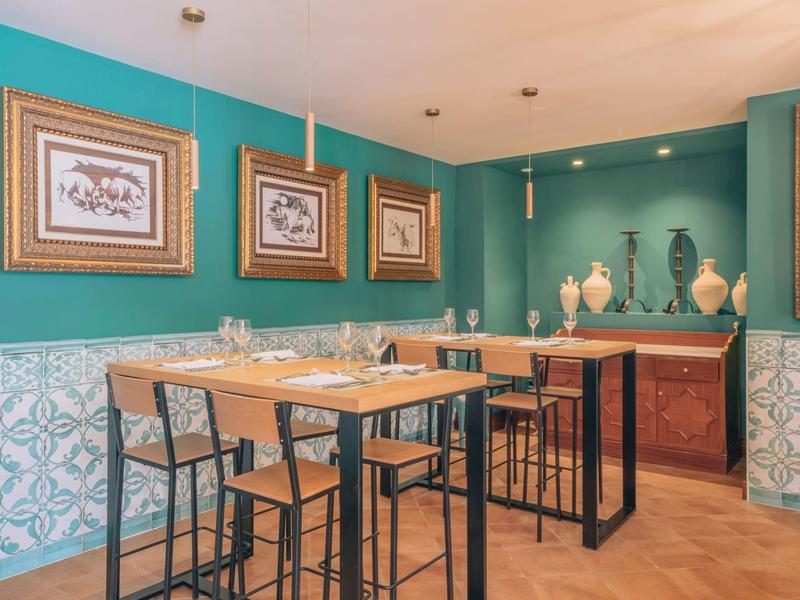 Gezellige eetruimte met houten tafels en hoge stoelen in een turquoise geschilderde kamer.