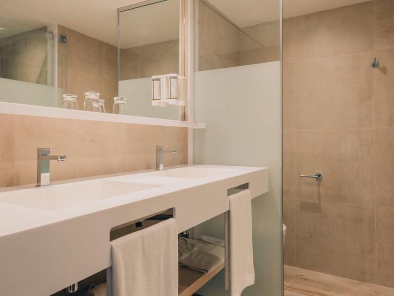 Moderne badkamer met dubbele wastafel, grote spiegels en glazen douche.