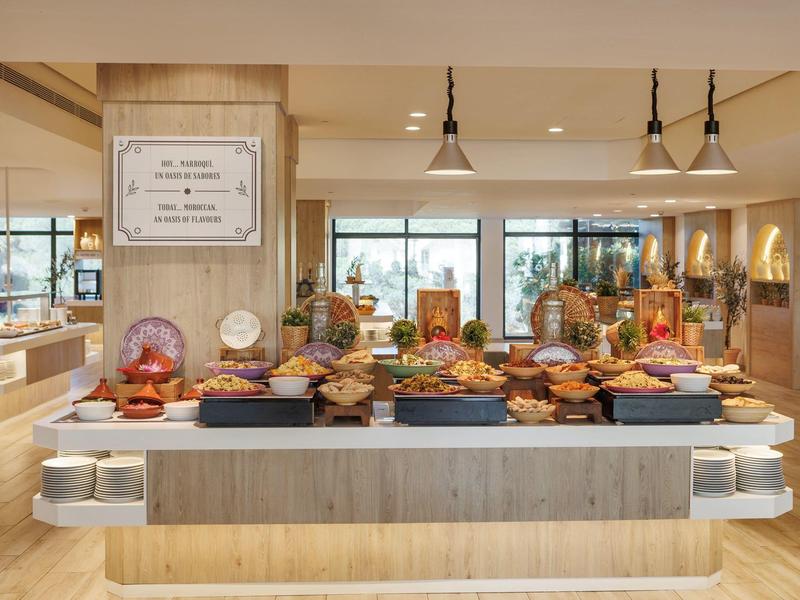 Buffet met diverse gerechten in een lichte restaurantruimte met grote ramen.