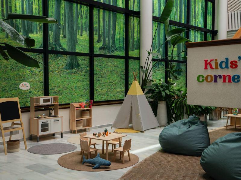 Kinderhoek met speelruimte, tafels, stoelen en comfortabele zitzakken in een lichte kamer.