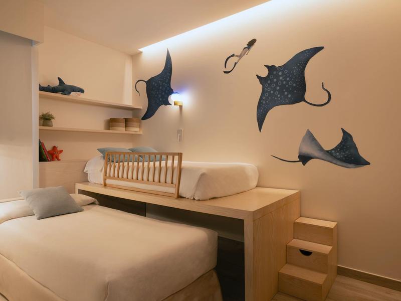 Moderne hotelkamer met twee bedden, pijlstaartrogwanddecoraties en een minimalistische houten trap.