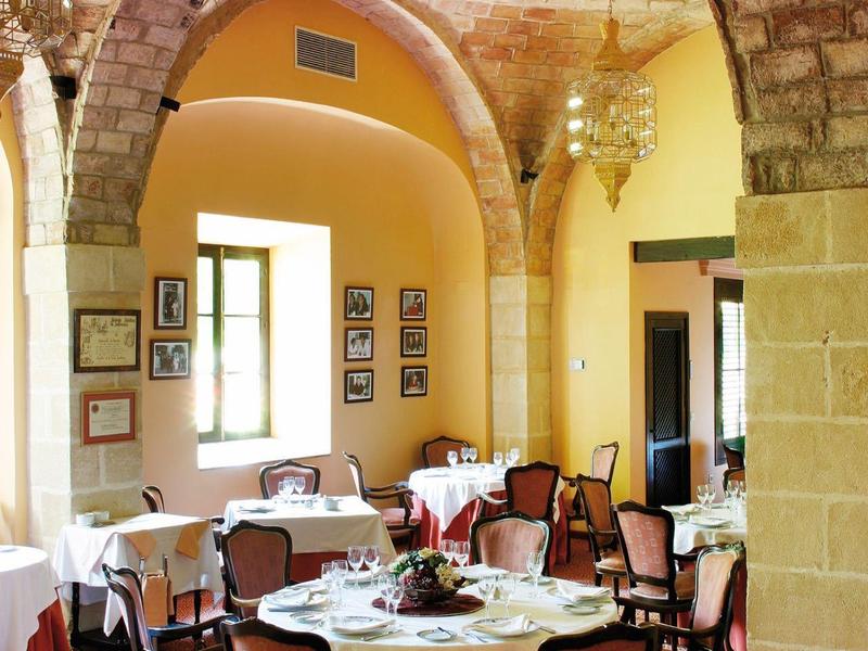 Salle à manger élégante avec plafonds voûtés en pierre et tables rondes dans un bâtiment historique.