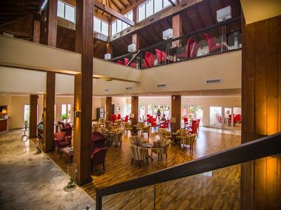 Großer, heller Gastraum mit Holzsäulen, roten Stühlen und bodentiefen Fenstern in gemütlichem Stil.