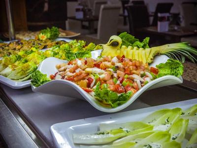 Verschiedene Salate in großen weißen Schalen mit frischem Gemüse und Garnelen, farbenfroh angerichtet.