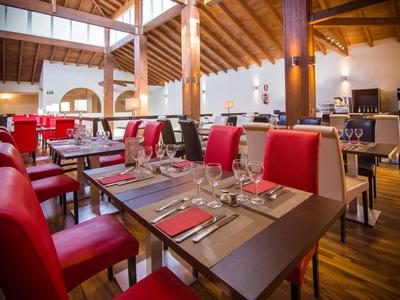 Modernes Restaurant mit roten Stühlen, Holzboden und gedeckten Tischen unter Holzbalken.