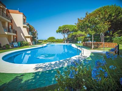 Runder Außenpool mit blauen Blumen und Sonnenlicht, umgeben von Gebäuden und Bäumen am Tag.