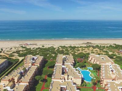 Blick auf Wohnanlage mit Pools, Strand und blauem Meer unter blauem Himmel.