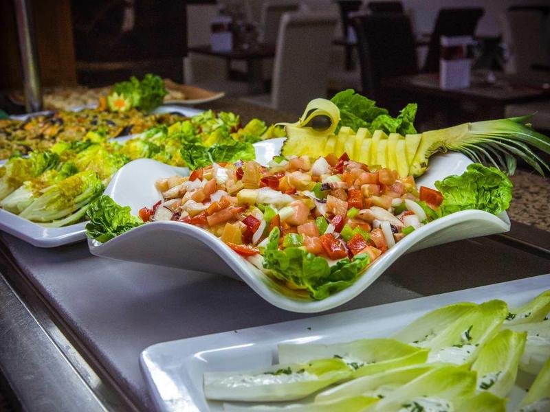 Verschiedene Salate in großen weißen Schalen mit frischem Gemüse und Garnelen, farbenfroh angerichtet.
