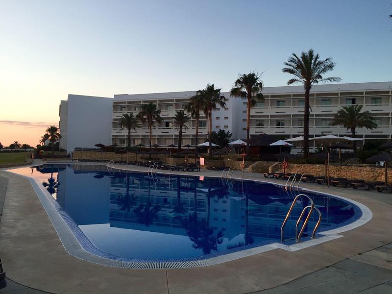 Scena serale alla piscina dell'hotel con palme e acqua calma