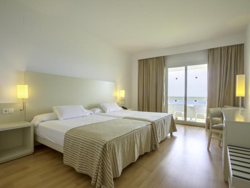 Camera d'hotel moderna con due letti singoli, balcone e vista mare.