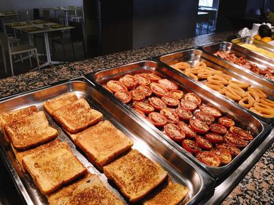 Buffet avec pain grillé, tomates grillées et saucisses dans une salle à manger.