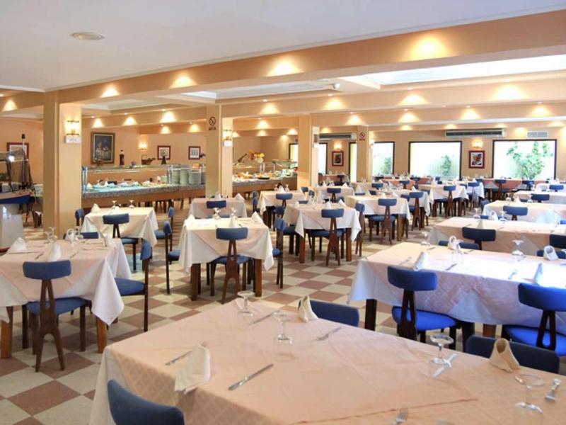 Grande salle à manger lumineuse avec des tables dressées et des chaises bleues dans un hôtel.
