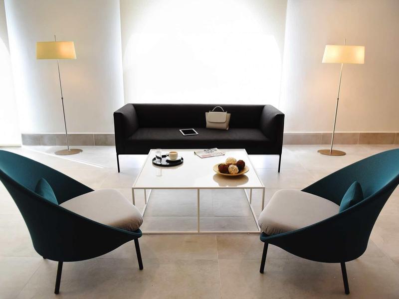 Espace d'attente moderne avec fauteuils élégants, canapé et table basse en verre.