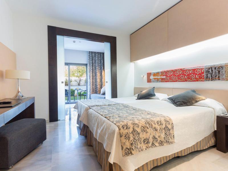 Modern hotel room with double bed, desk, and access to a terrace.