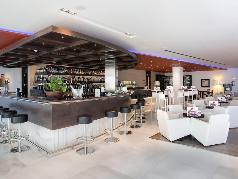 Modern hotel bar with white armchairs and bar stools, bright elegant interior