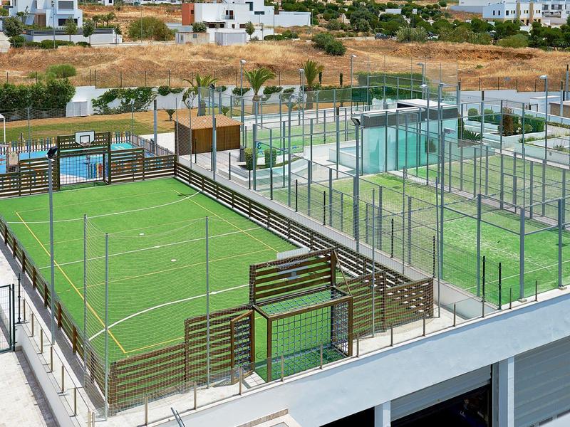 Several green fenced sports courts on a building rooftop terrace.