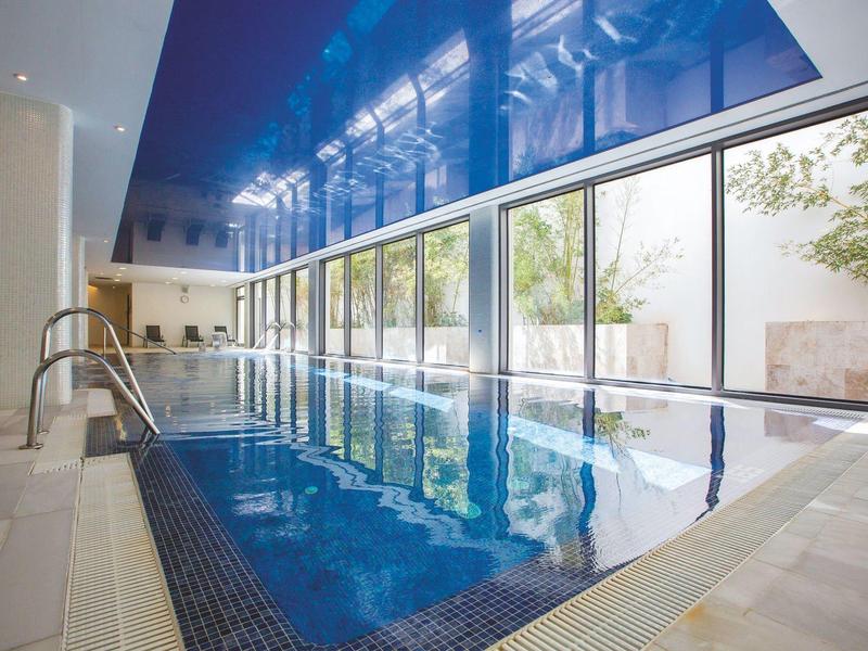 Indoor hotel pool with large windows and a relaxing atmosphere.