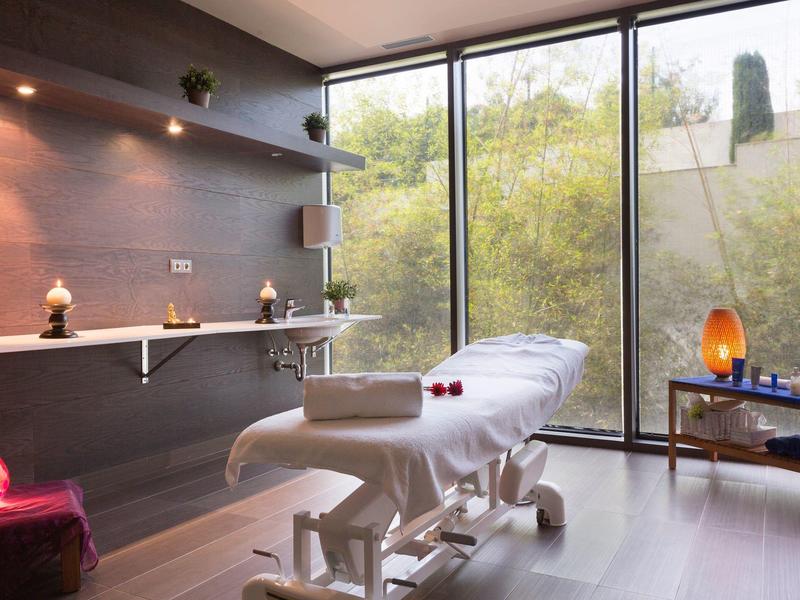 Bright wellness room with massage table, large windows, and relaxing atmosphere.