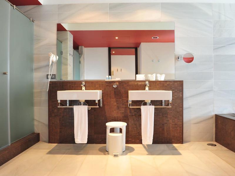 Modern bathroom with two sinks, mirrors, and glass shower in a hotel.