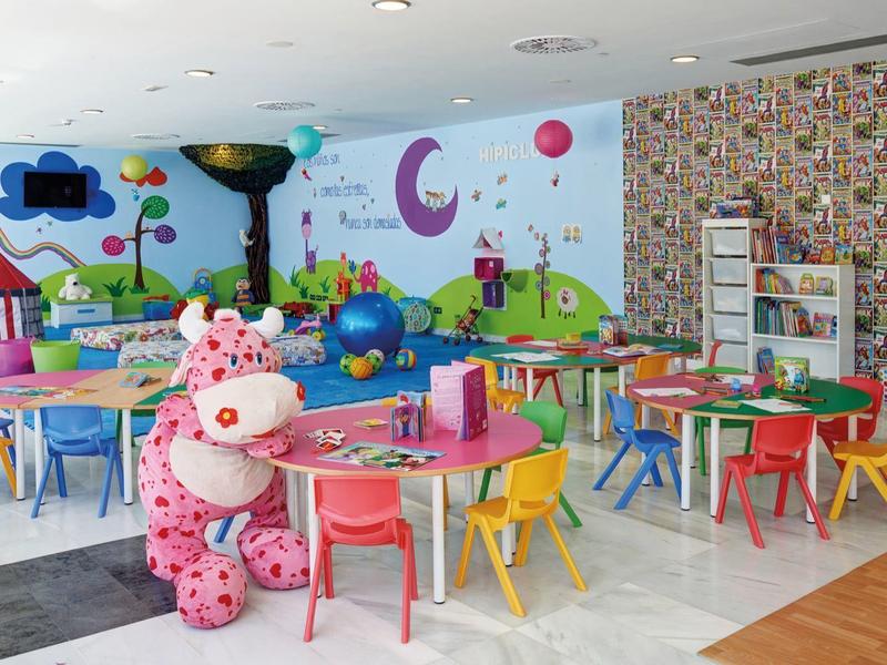 Colorful kids' playroom with small tables, colorful chairs, and playful wall decorations.