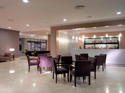 Großer heller Raum mit mehreren dunkelbraunen Stühlen und Tischen vor einer beleuchteten Bar.