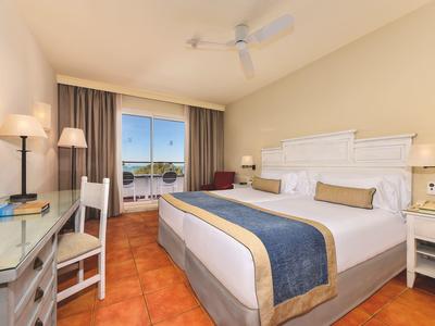 Moderne hotelkamer met groot bed, bureau, tv en balkon met uitzicht.