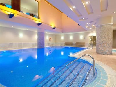 Overdekt zwembad met blauwe tegels, metalen leuning en warme indirecte verlichting.