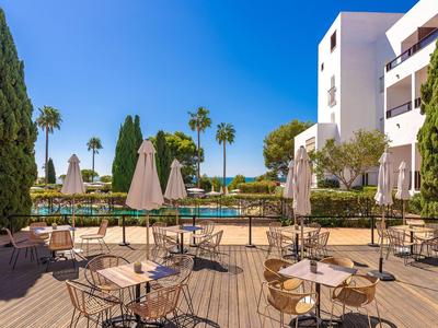 Terras met tafels en stoelen voor hotelgebouw onder een heldere hemel