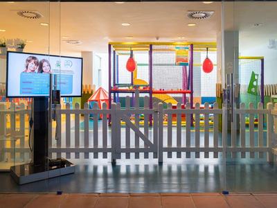 Moderne, lichte kinderspeelruimte in hotel met digitaal displaybord.