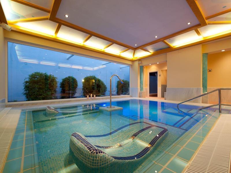 Moderne binnenzwembad met ingebouwde jacuzzi en ontspannen sfeer.