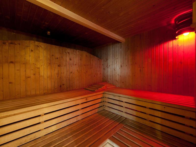 Sauna met houten banken en rood licht aan de muur voor een ontspannen sfeer.