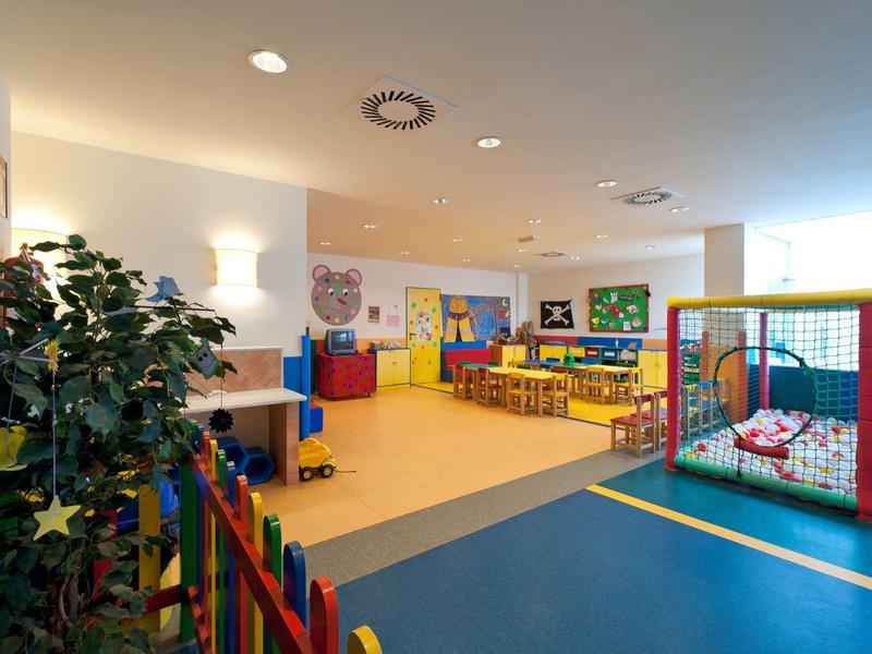 Goed verlichte speelruimte voor kinderen met klimrek, kleurrijk meubilair en tafels binnen.